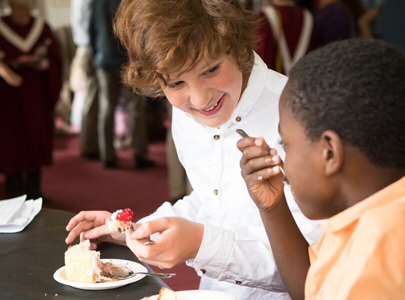 Two teenage boys smile and eat cake at church