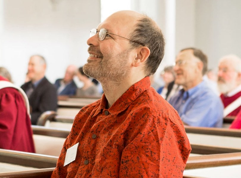 A man smiles while listening to a sermon