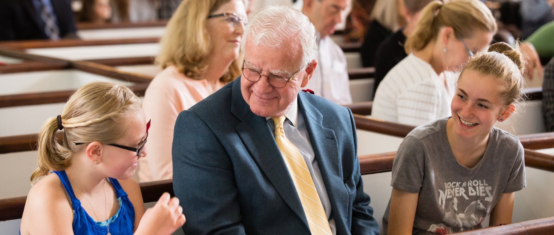 A father sits in the pews and talks with his two teenage daughters.