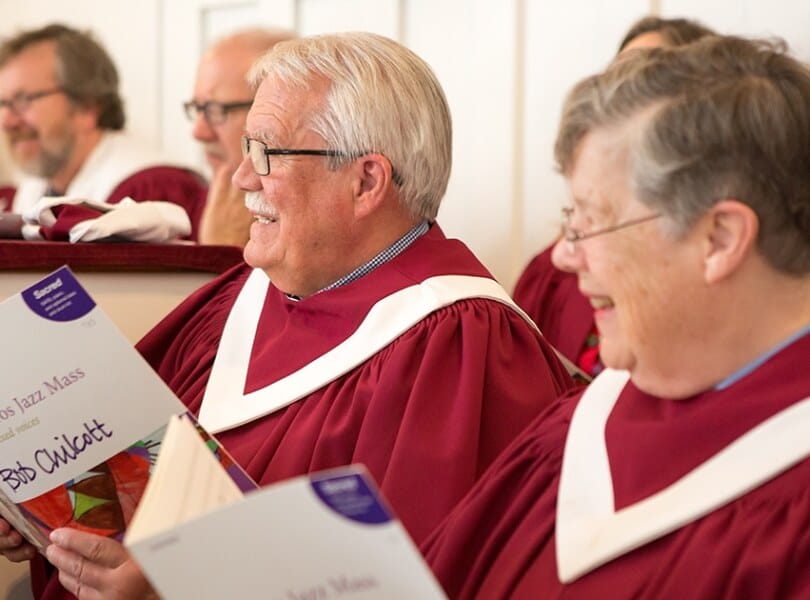 Members of the choir smile while looking at the Minister of Music