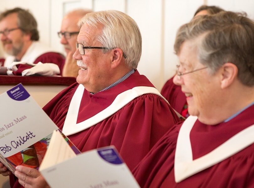 Members of the choir smile while looking at the Minister of Music
