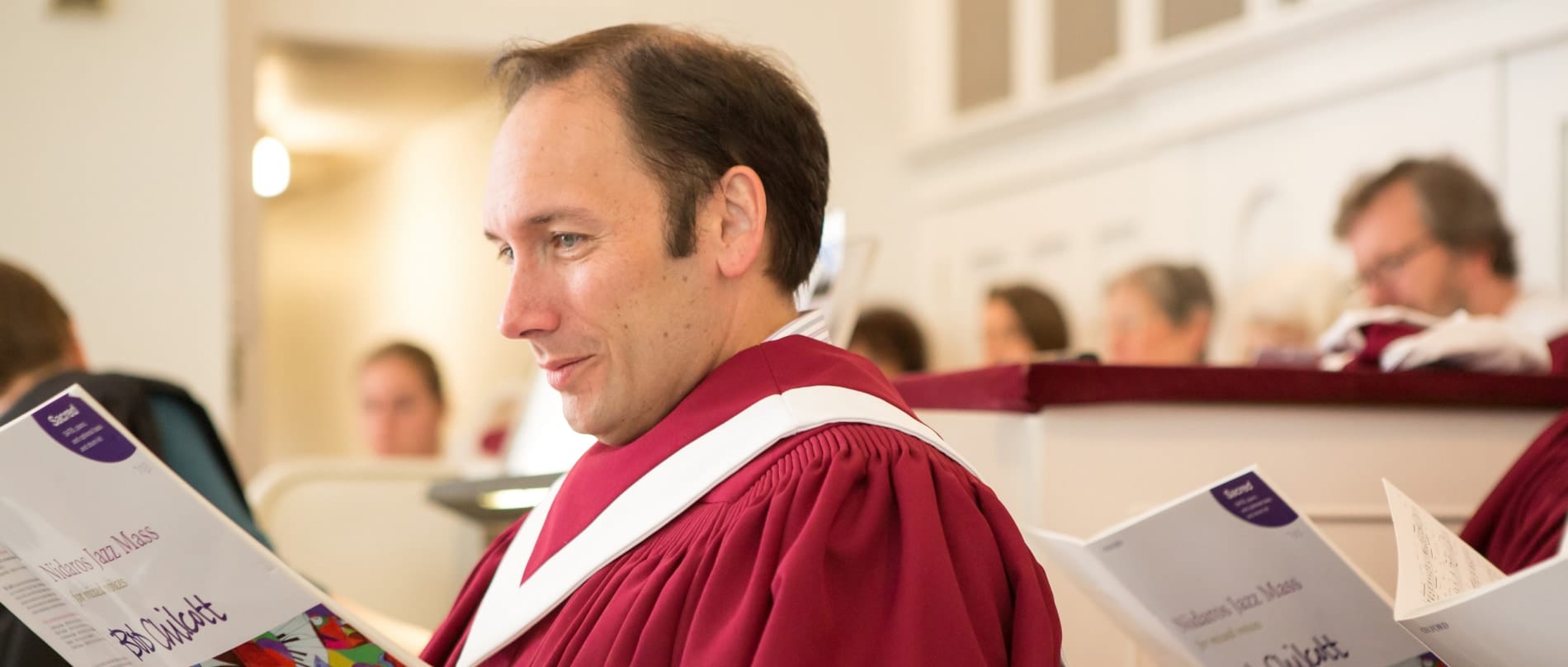 A young man studies his music during choir rehearsal
