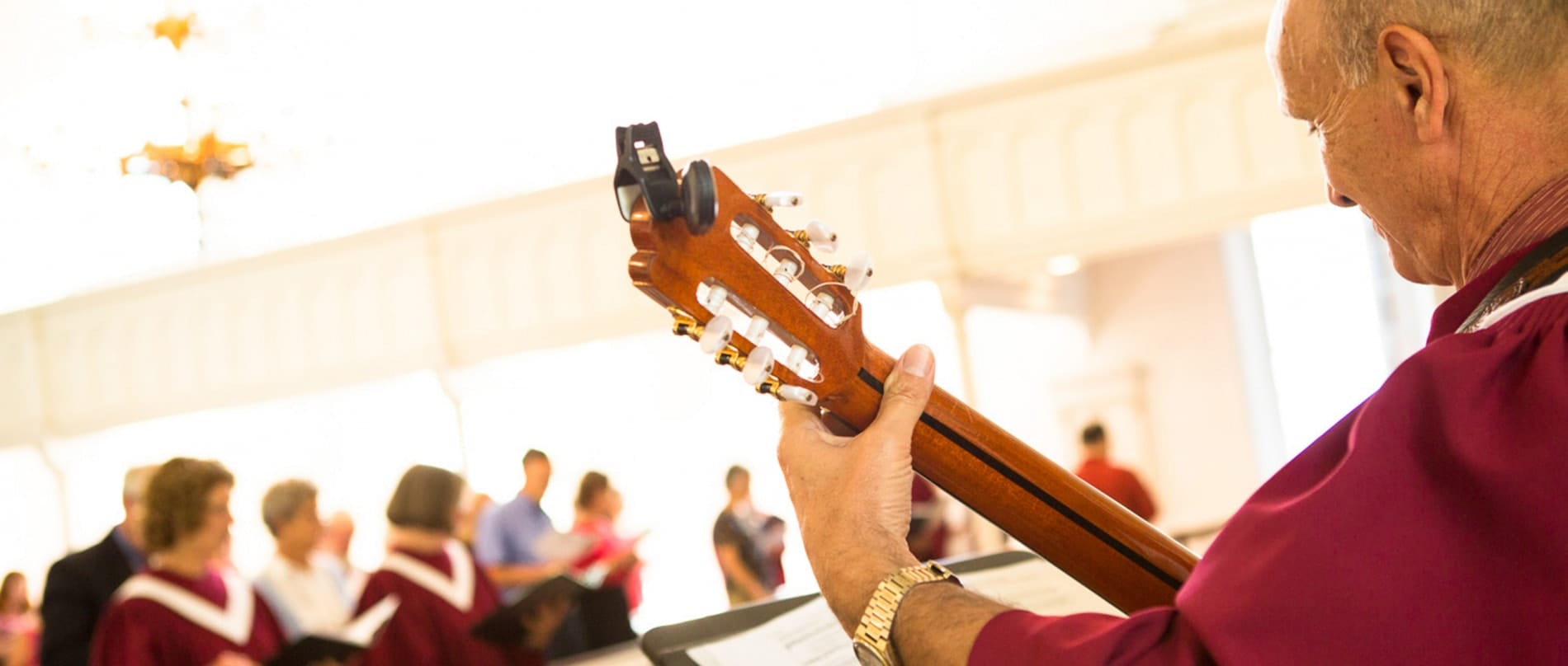 A man plays classical guitar. Close up shot of his guitar neck.