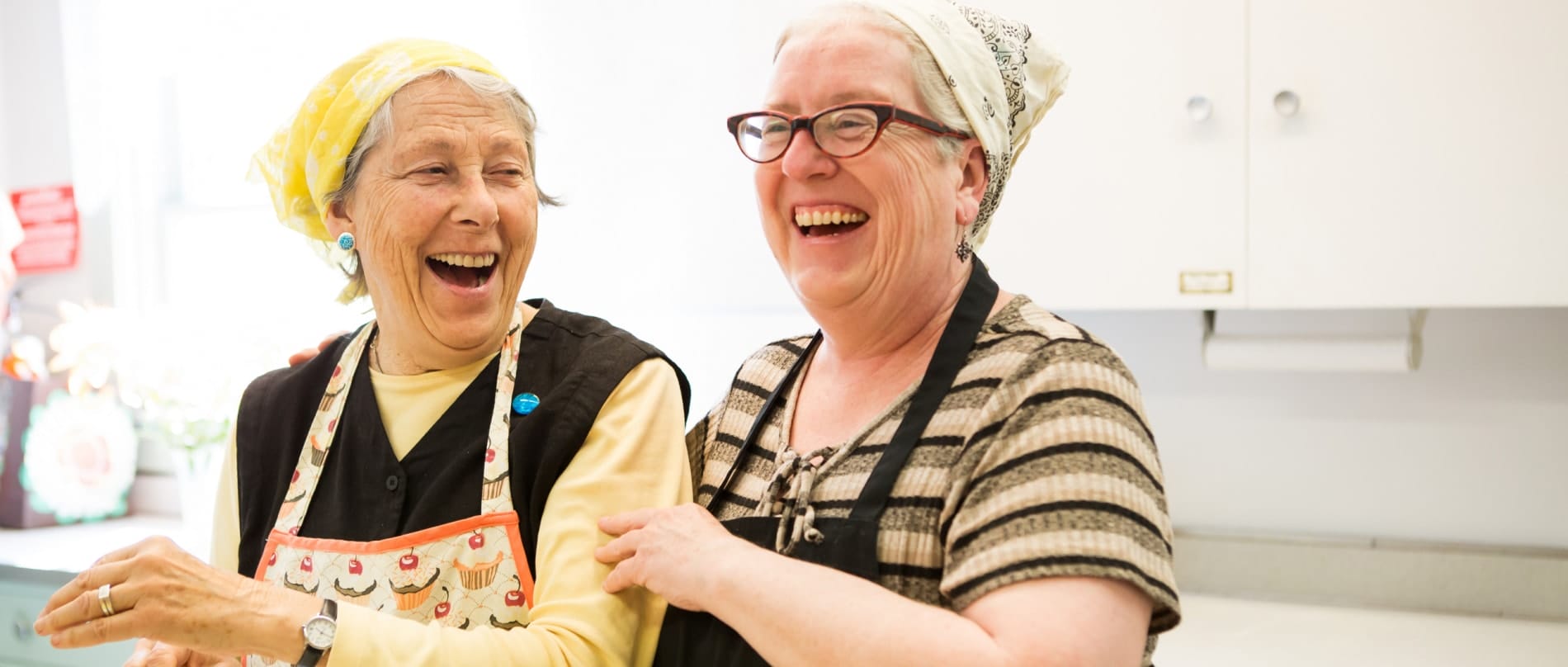 Two women laugh while prepping a meal for Berkshire county's homeless.