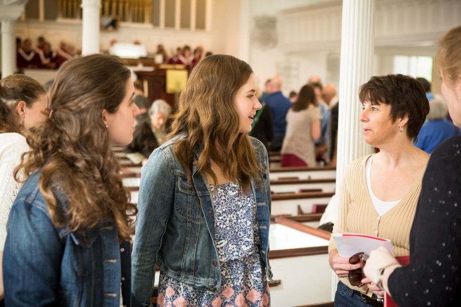 A woman chats with two young women in the sanctuary