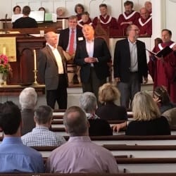 A group of men sings a cappella