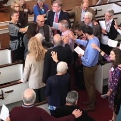 Congregants lay their hands on Pastor Brent to bless him