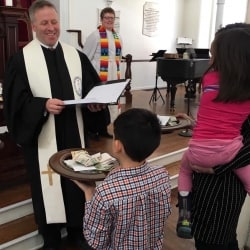 Rev. Brent Damrow receives the offering from a group of children