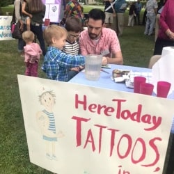 A man applies tattoos to a boy
