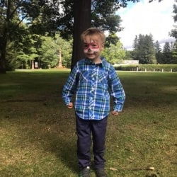 A young boy with his face painted like a fox.