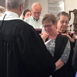 A tearful minister of music receives a blessing from the congregation
