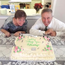 Cathy Schane-Lydon and Brent Damrow smile in front of a farewell cake