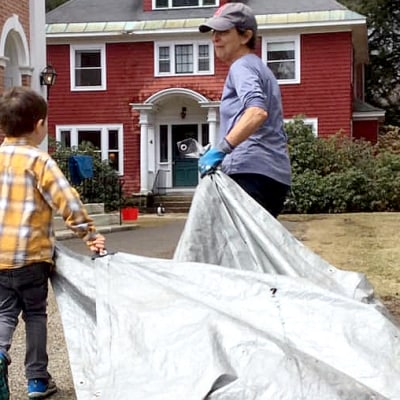 A boy helps haul leaves in a tarp