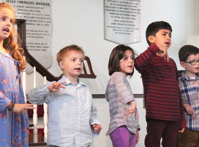 Three boys and two girls sing in church