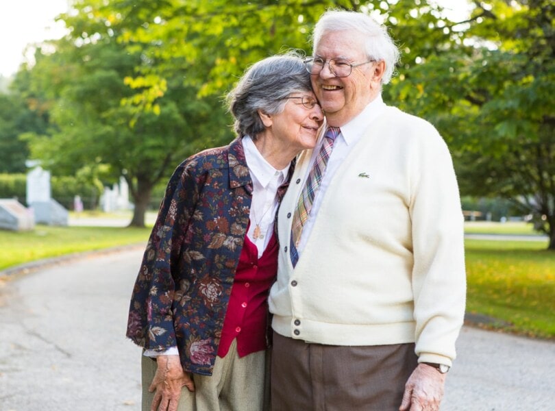 An elderly wife and husband laugh and hug each other