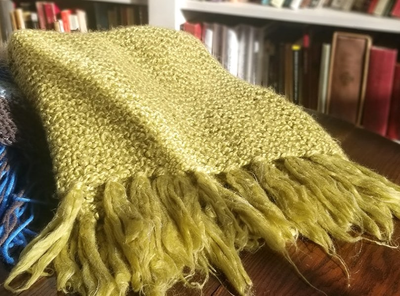 A green prayer shawl and a blue prayer shawl on a wooden table