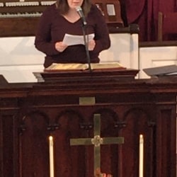 A woman reads the call to worship from the pulpit