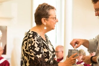 A woman serves communion to a man