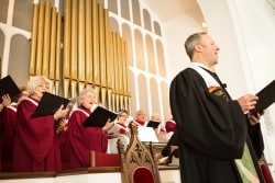 The pastor and members of the church choir sing a hymn