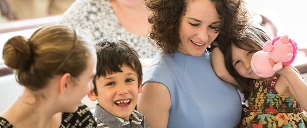 A mother and her two children hug in the church pews