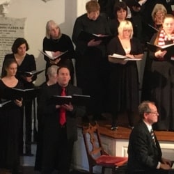 Tenor soloist Steve Hassmer sings a solo while accompanied by chorus and piano