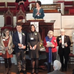 A mix of men and women of all ages stand before the church as they become members