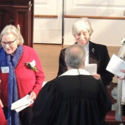 The pastor shakes the hand of an older woman to welcome her into the church