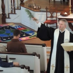 The pastor sprinkles members of the congregation with water as a symbol of baptism
