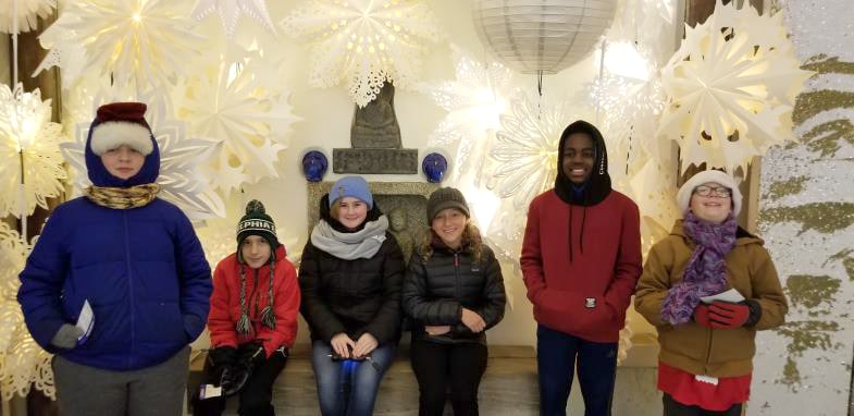 A group of pre-teens in front of a winter lights display